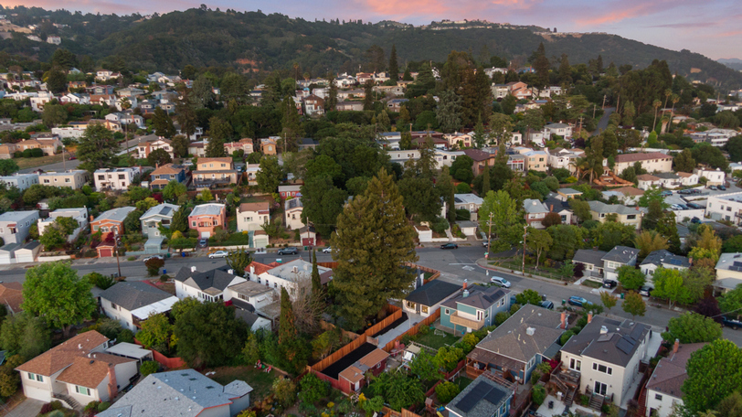 Aerial view showcasing the property's location within a charming hillside neighborhood with mature trees and residential streets.