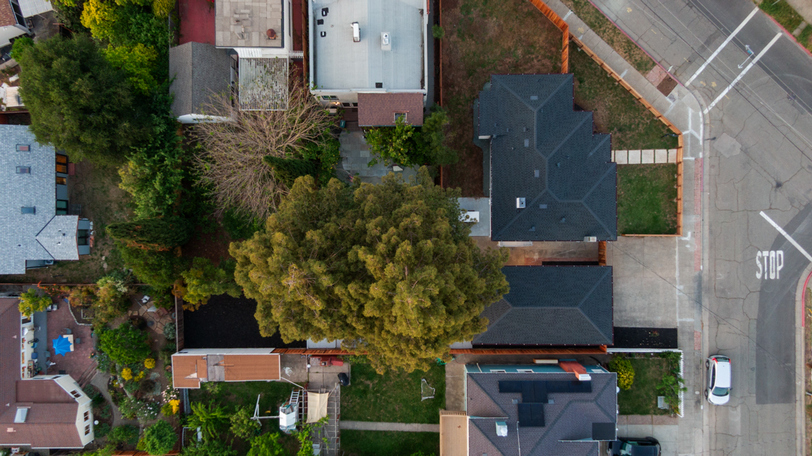 Bird’s-eye view highlighting the corner lot, detached structures, mature trees, and overall property layout.