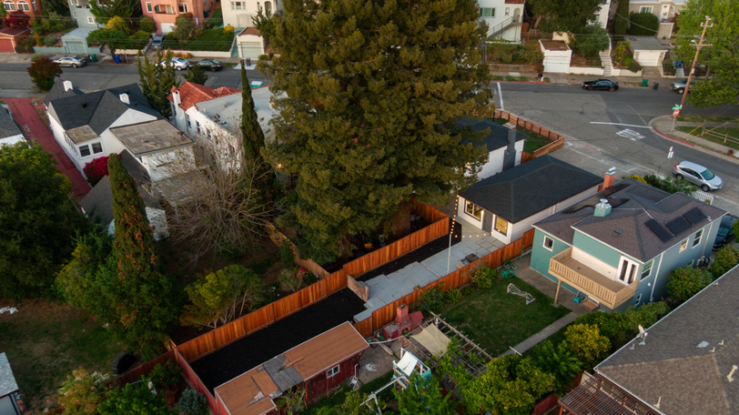 Aerial view showcasing the expansive lot, mature redwood trees, and beautifully landscaped outdoor spaces in a desirable corner-lot setting.
